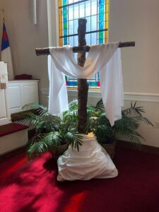 A cross draped with white cloth in a church setting.