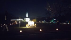 Night scene with a lit wagon and glowing lanterns near a church steeple.