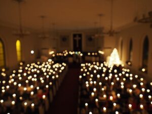 Blurry image of a church filled with candlelight and a glowing Christmas tree.