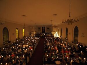A large congregation holds candlelight vigil inside a church at night.