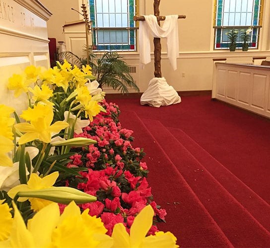 Statue of Jesus with colorful flowers in a church setting.
