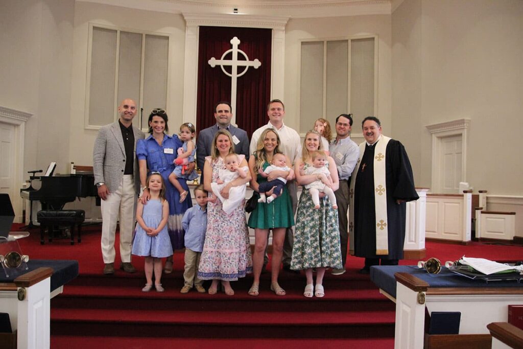 A family posing together in a church with clergy members.