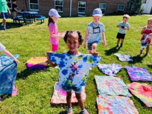 Children playing and painting shirts outdoors on a sunny day.