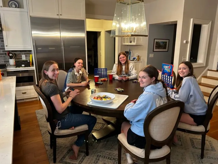 Five friends enjoying a meal together around a dining table.
