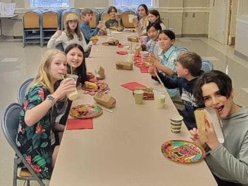Group of teenagers enjoying a meal together at a long table.