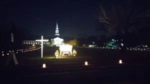Night scene with a lit wagon and glowing lanterns near a church steeple.