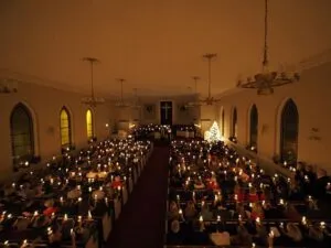 A large congregation holds candlelight vigil inside a church at night.