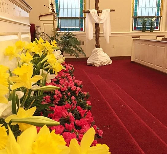 Statue of Jesus with colorful flowers in a church setting.