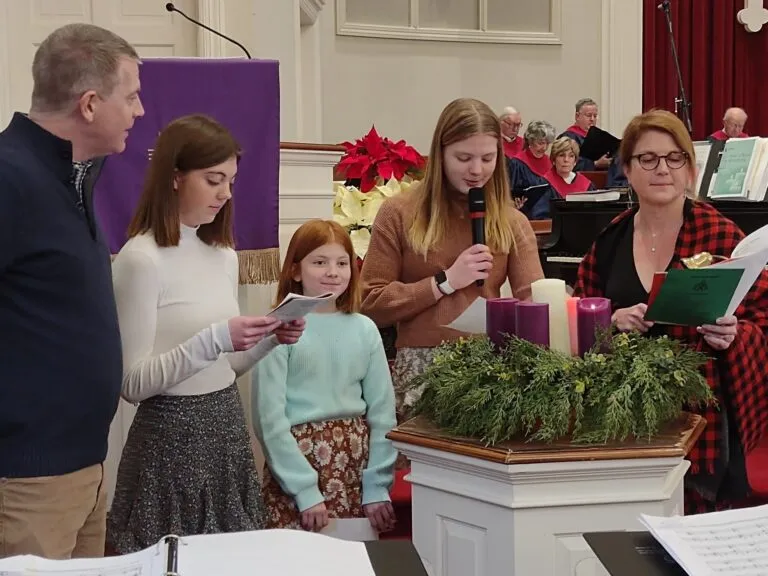 A group of girls reading from cards during a church service.