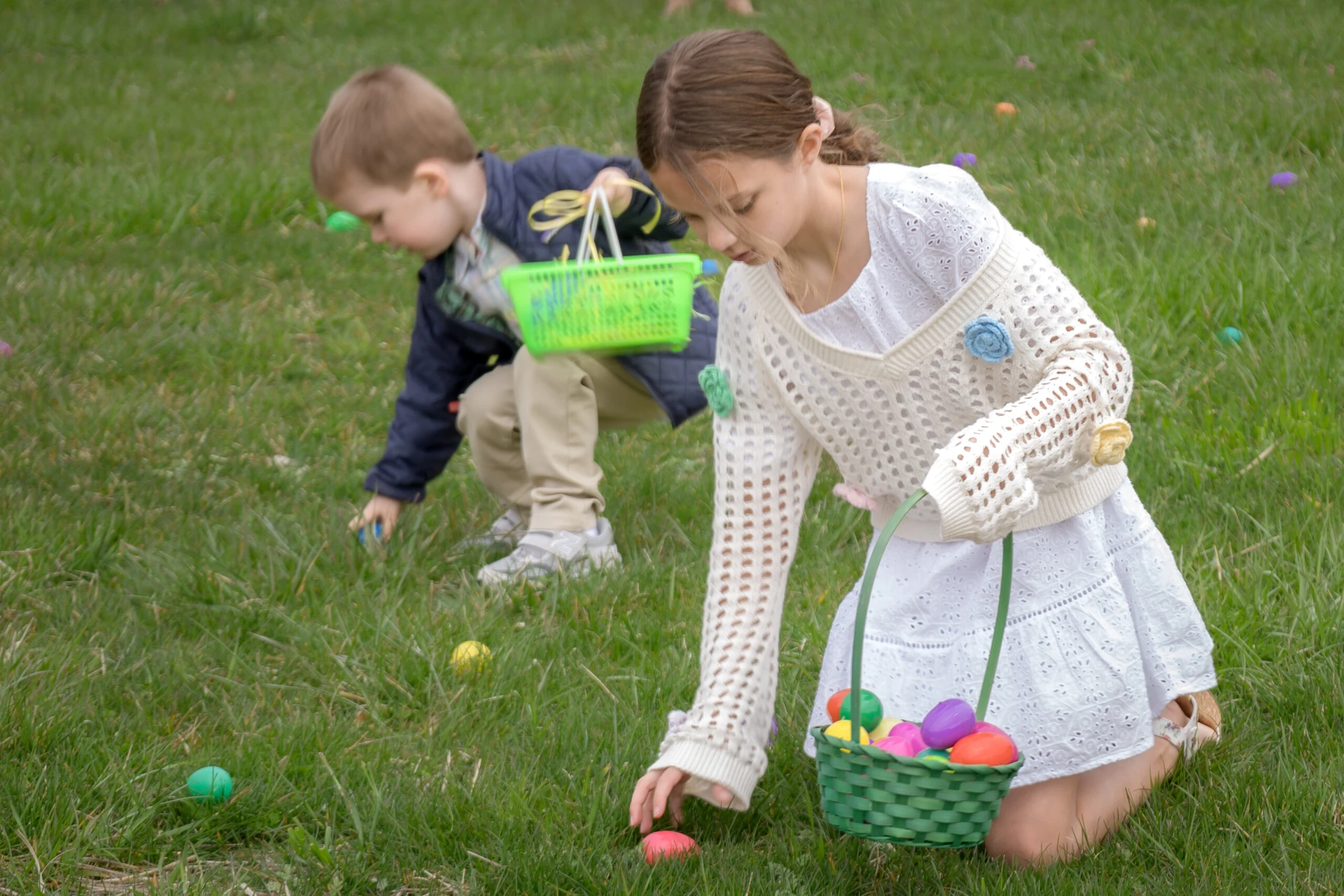 Children collecting Easter eggs outdoors on grass.