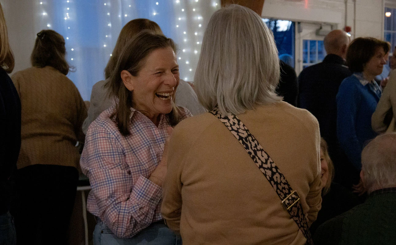 Two women sharing a joyful moment at a social gathering.