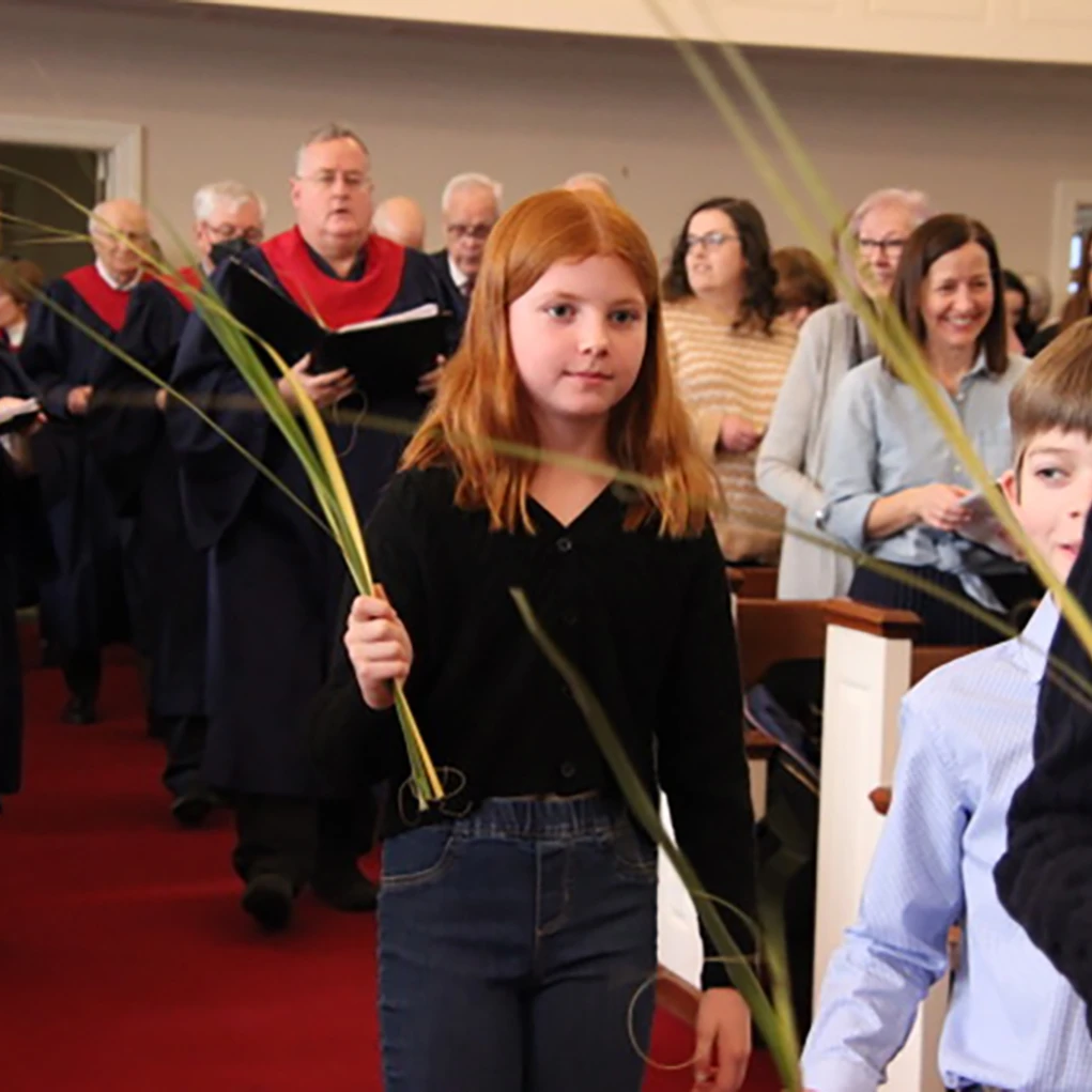 Girl holding a palm branch during a church service.