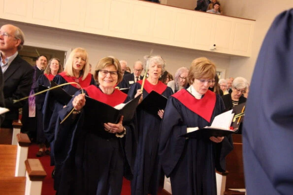 Older women in choir robes singing in a church setting.