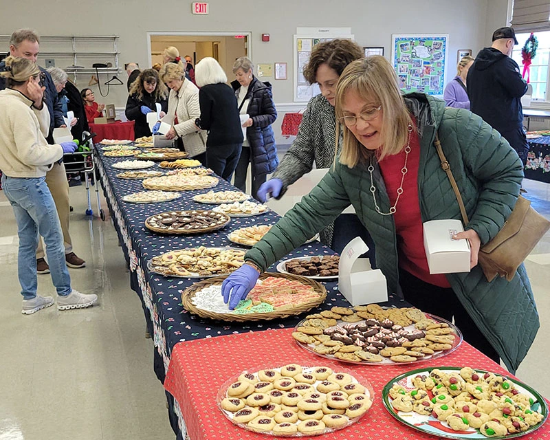 People serving various pies at a community event.