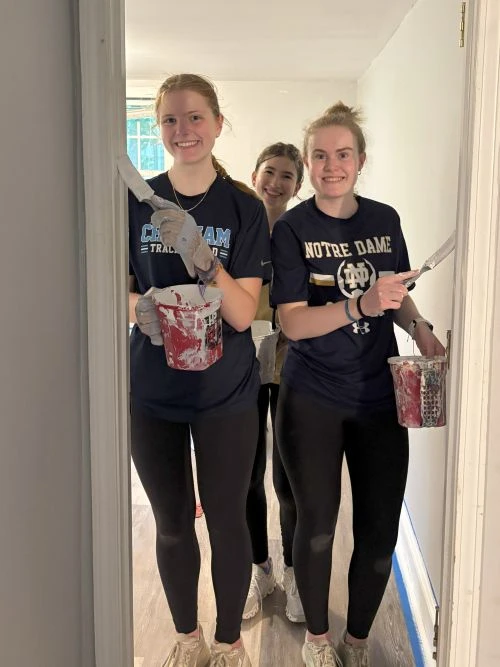 Two women in casual black outfits holding popcorn, posing in front of a mirror.