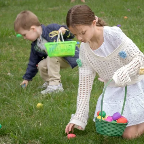 Children collecting Easter eggs outdoors on grass.