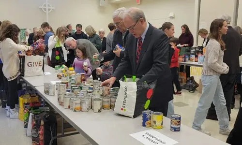 People shopping at a canned goods sale in a community hall.