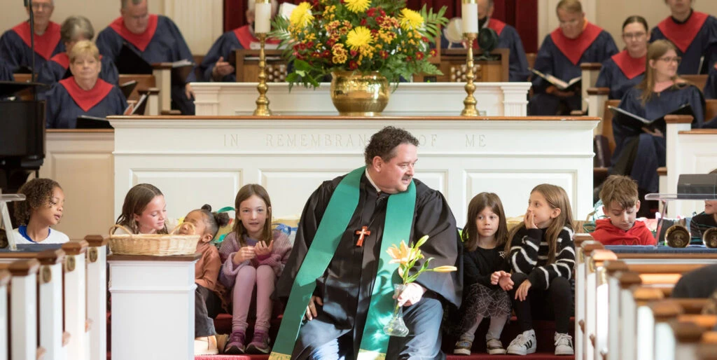 Pastor Tom Brown sitting amidst children in church